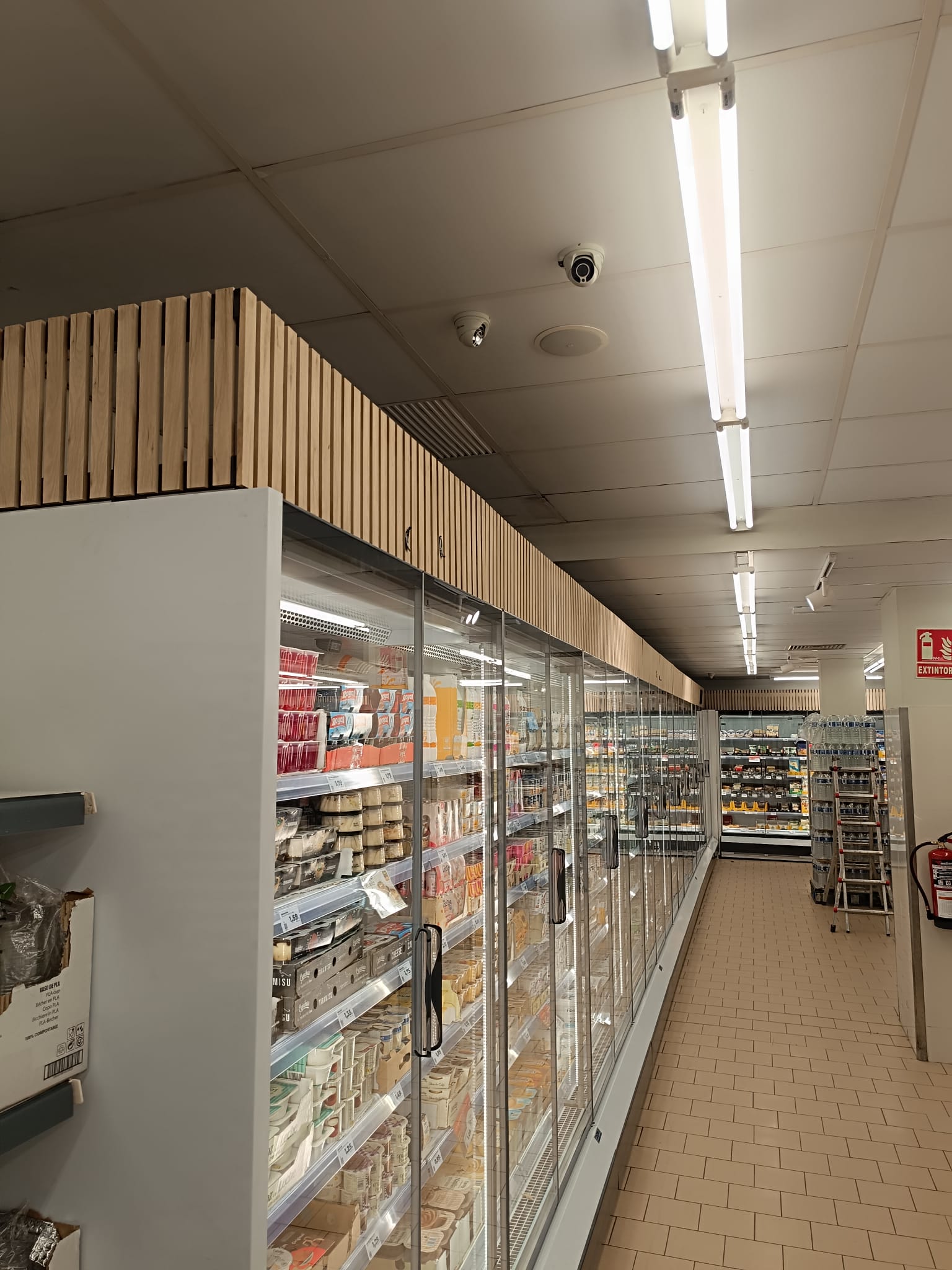 Lineal refrigerado terminado con remate superior en lamas de madera en entorno comercial